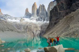Journal 4 Group of hikers posing on a boulder by a turquoise glacial lake beneath tall granite peaks in Patagonia